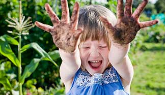 Child with dirty hands from gardening.