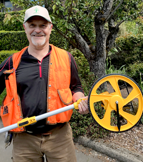 treekeeper in orange vest holding measuring equipment