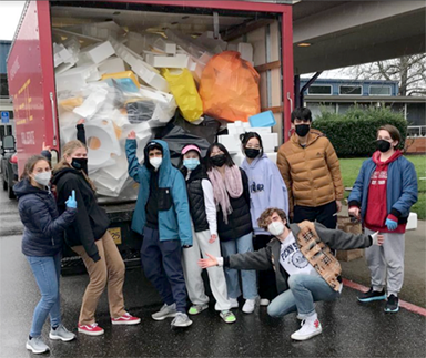 students pose in front of full recycling truck