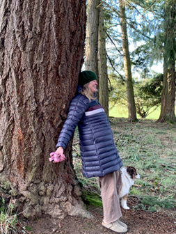 person leaning on tree with dog