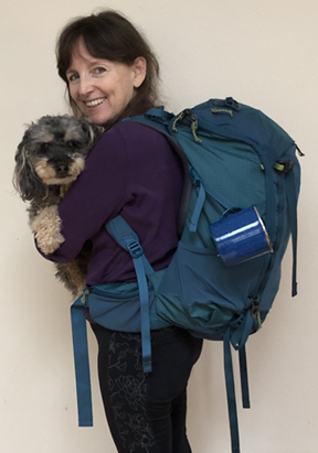 smiling woman with backpack carrying dog