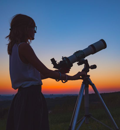 person viewing night sky through telescope