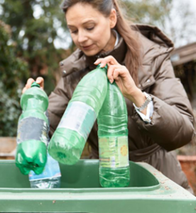 person recycling bottles in green bin